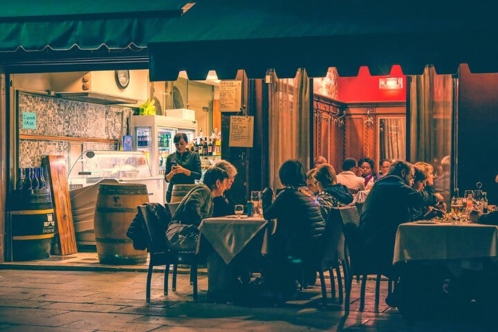 Terraza exterior de un bar en Venecia con gente sentada de noche