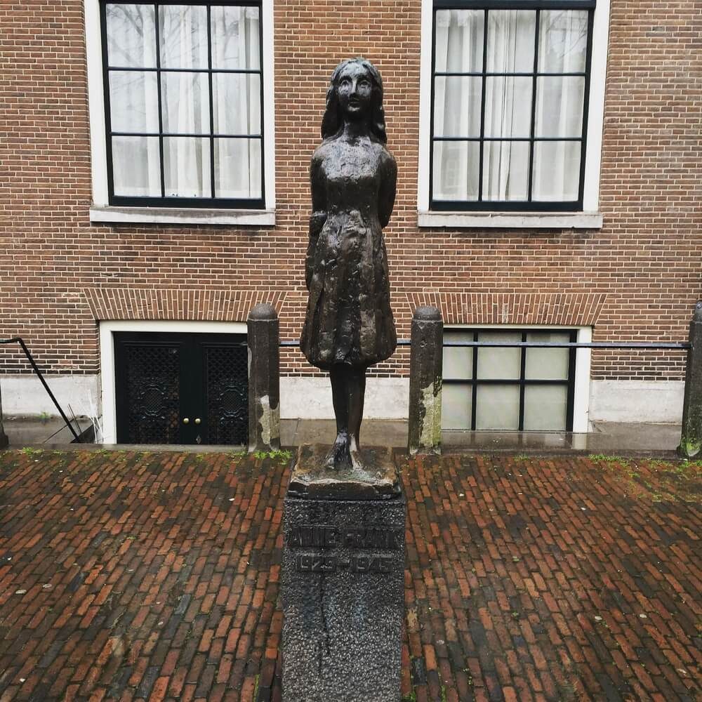 Estatua de Ana Frank delante de las ventanas de la  casa museo Annefrankhuis en Ámsterdam