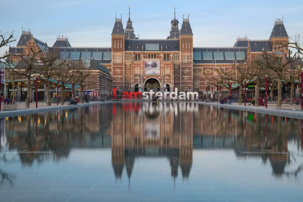 Fachada principal del Museo Nacional de Ámsterdam o Rijksmuseum con estanque y letras I amsterdam en frente