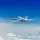 Un avión vuela sobre las nubes en un cielo azul
