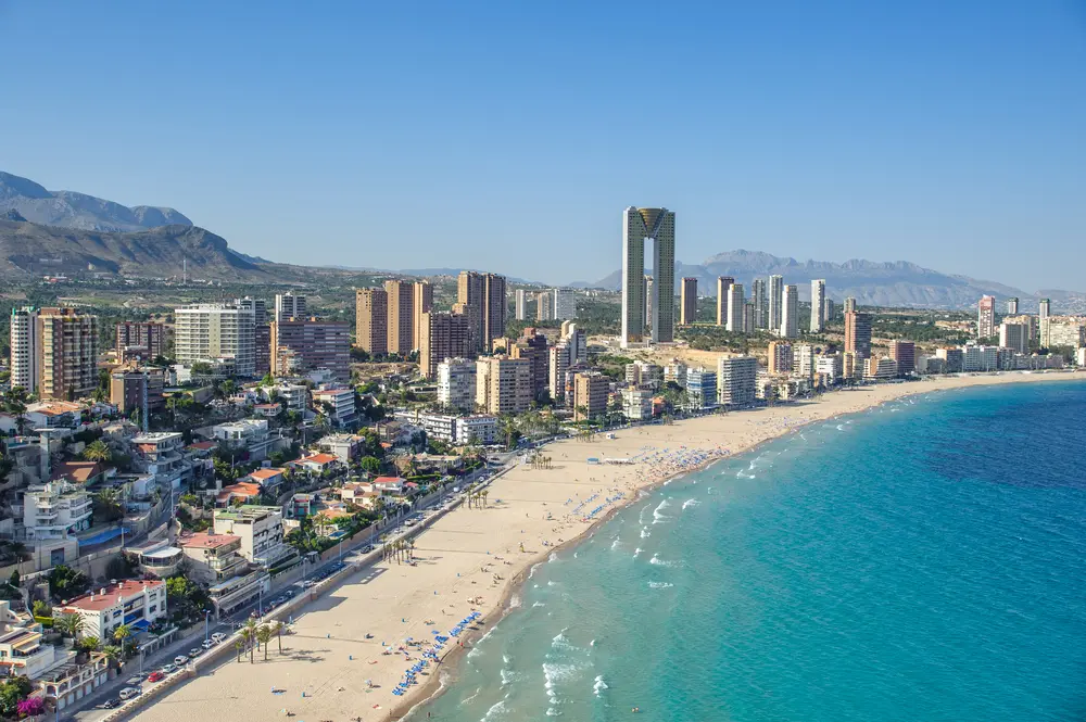 Vista de la playa de Benidorm con los edificios de fondo y el mar a la derecha.