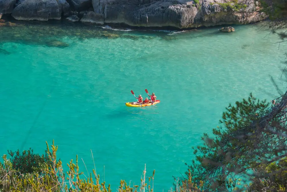 Dos personas practican Kayak en las aguas turquesas de Cala en Porter, Menorca