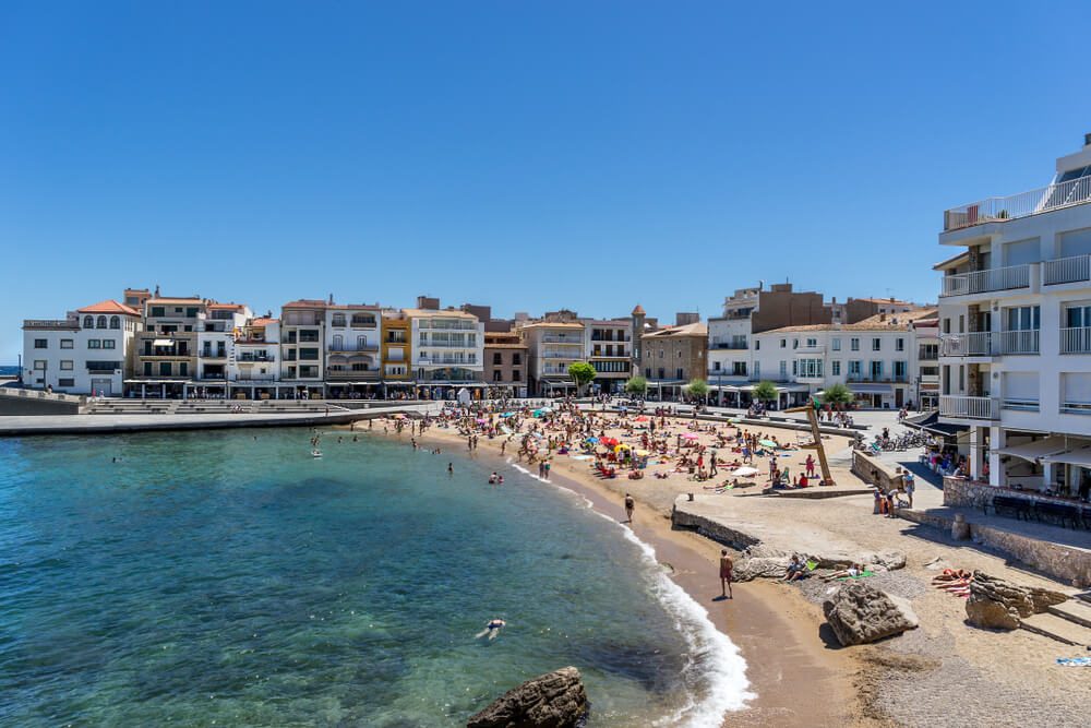 Playa central de L'Escala con bañistas y edificios del casco antiguo del pueblo, en Girona