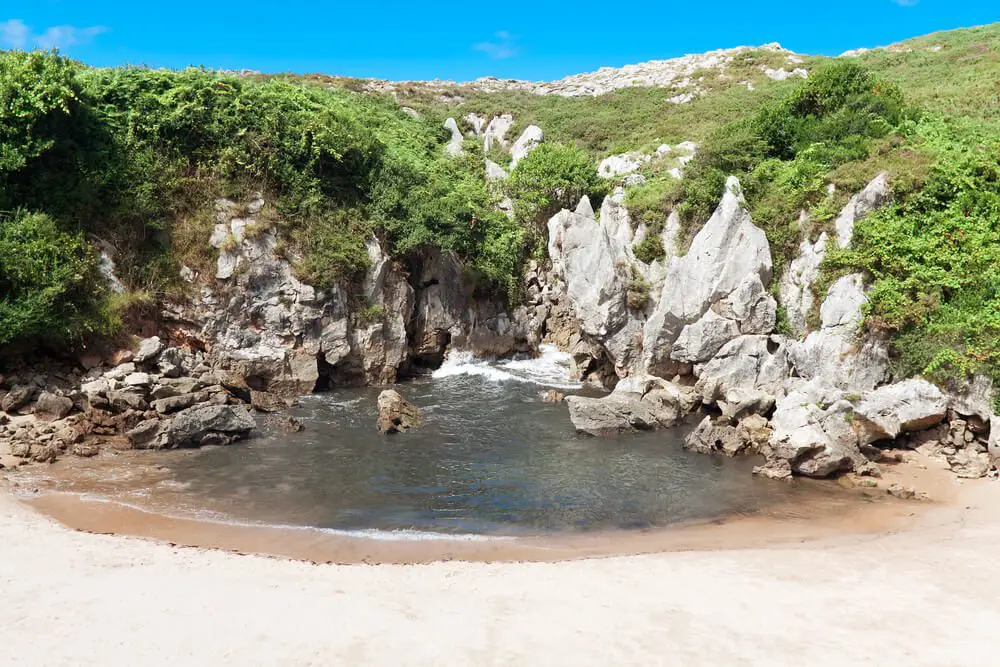 Playa de Gulpiyuri con agua tierra adentro y arenal cerca de Llanes, Asturias