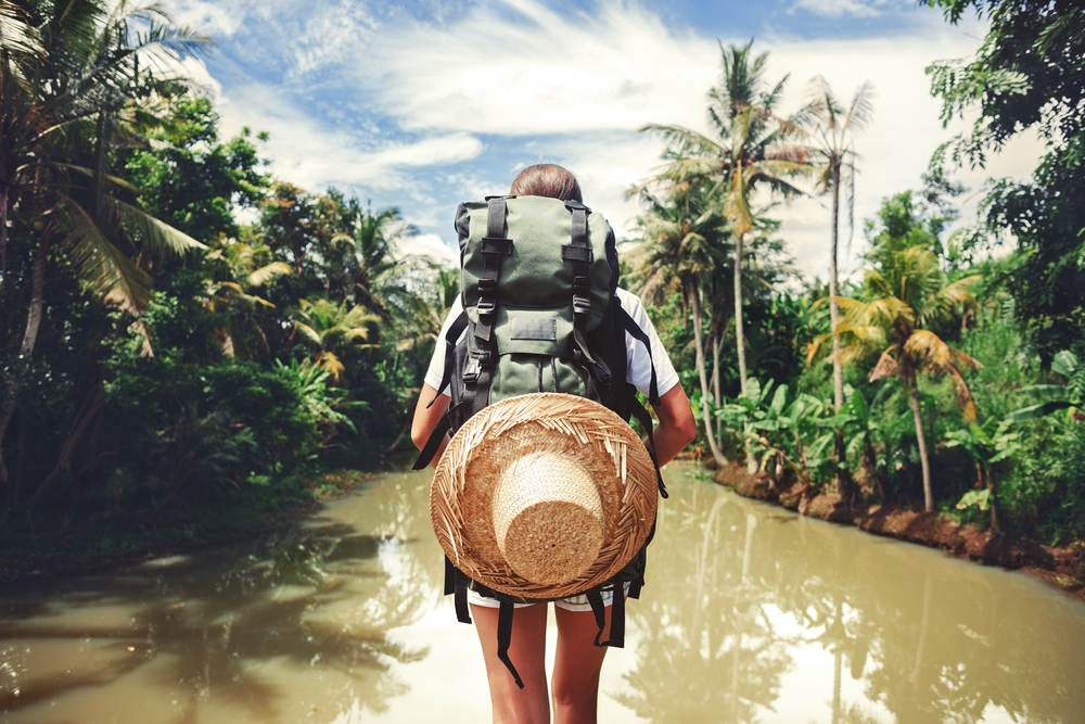 mujer viajera con mochila con rio tropical