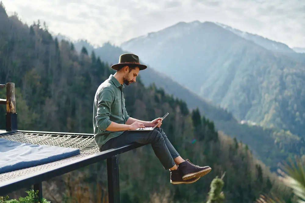 bloguero de viajes escribiendo con su portatil con panorama montañas