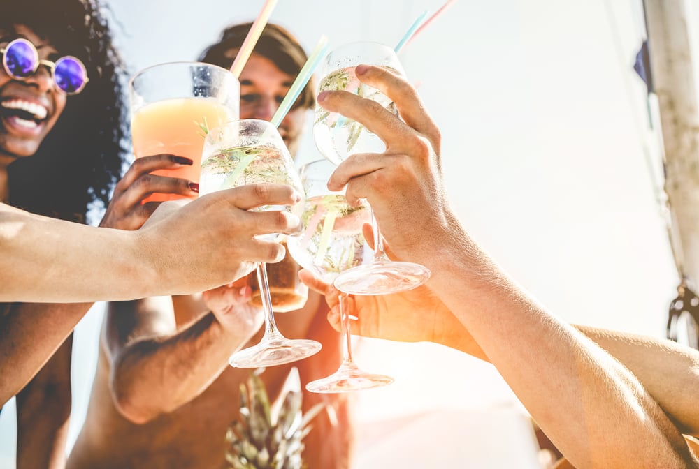 Grupo de amigos felices con cócteles en la playa