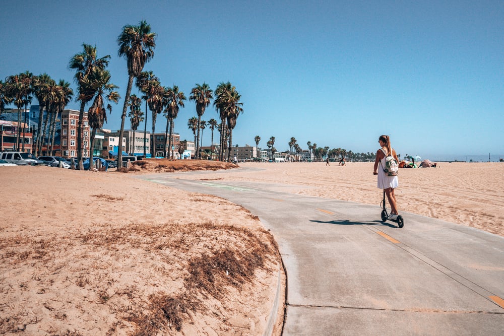 chica en patinete electrico en la playa