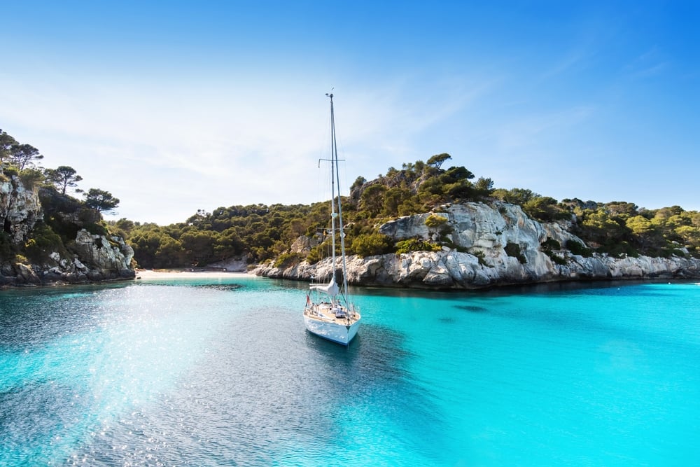 playa con velero menorca