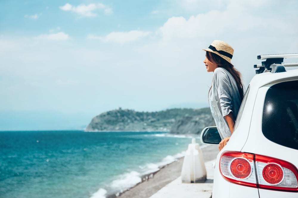 mujer en coche con vistas al mar en viaje de verano a la playa en menorca