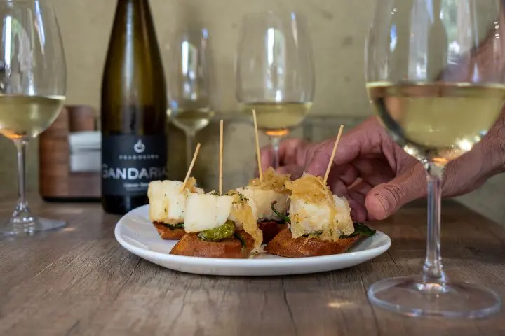 Plato de pintxos y copas de txakoli en un bar de pintxos.