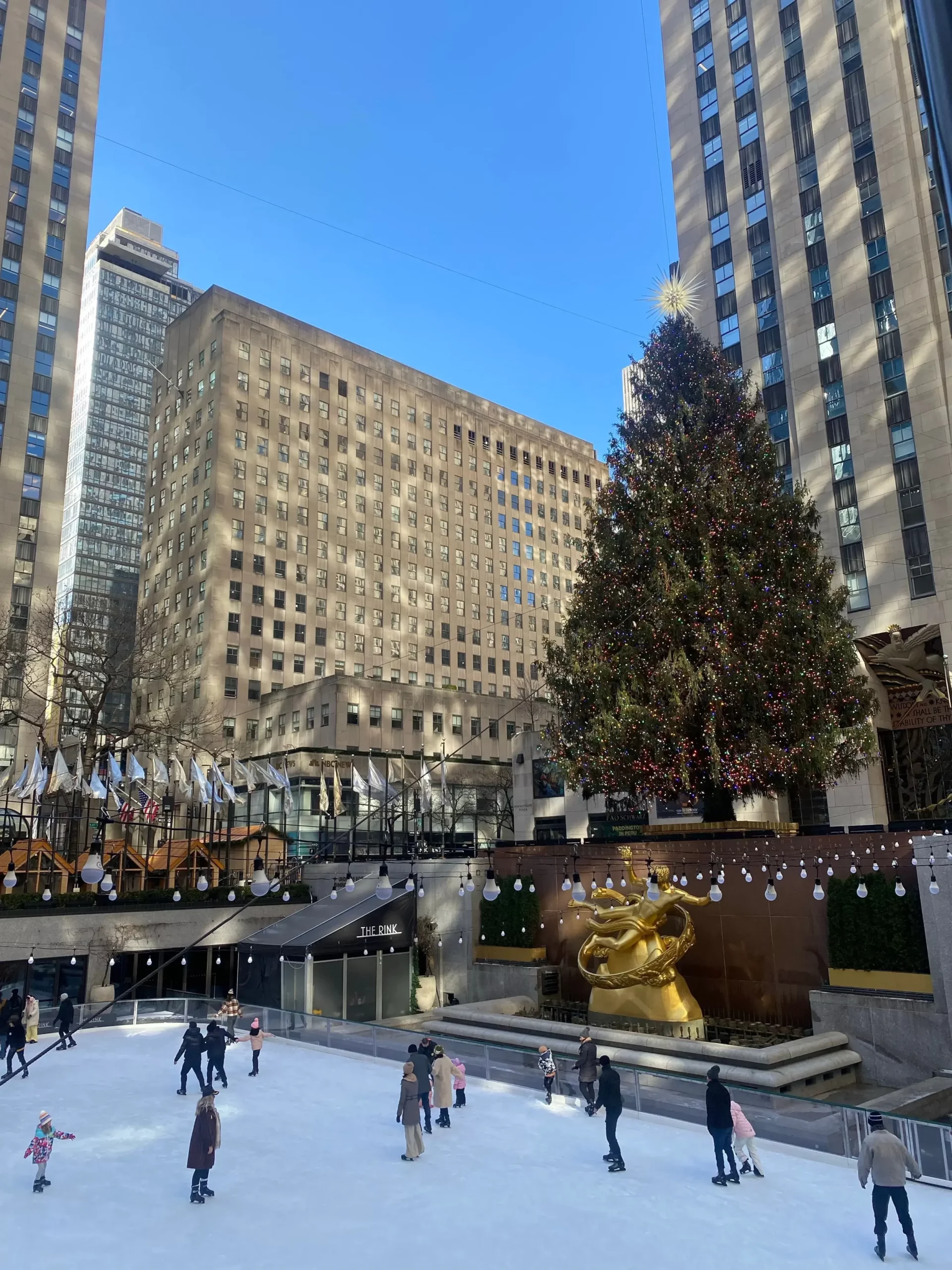 Gran árbol de Navidad iluminado junto a una pista de patinaje al aire libre en Nueva York, una de las tradiciones navideñas más icónicas de Estados Unidos