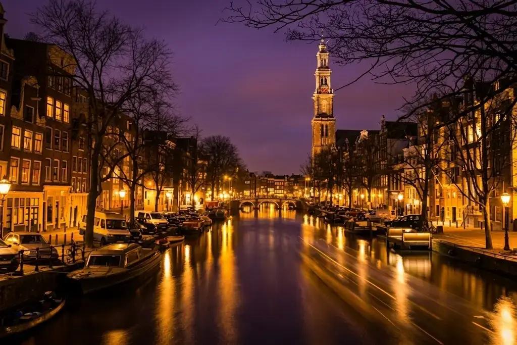 Edificios iluminados en los canales de Ámsterdam reflejados en el agua por la noche
